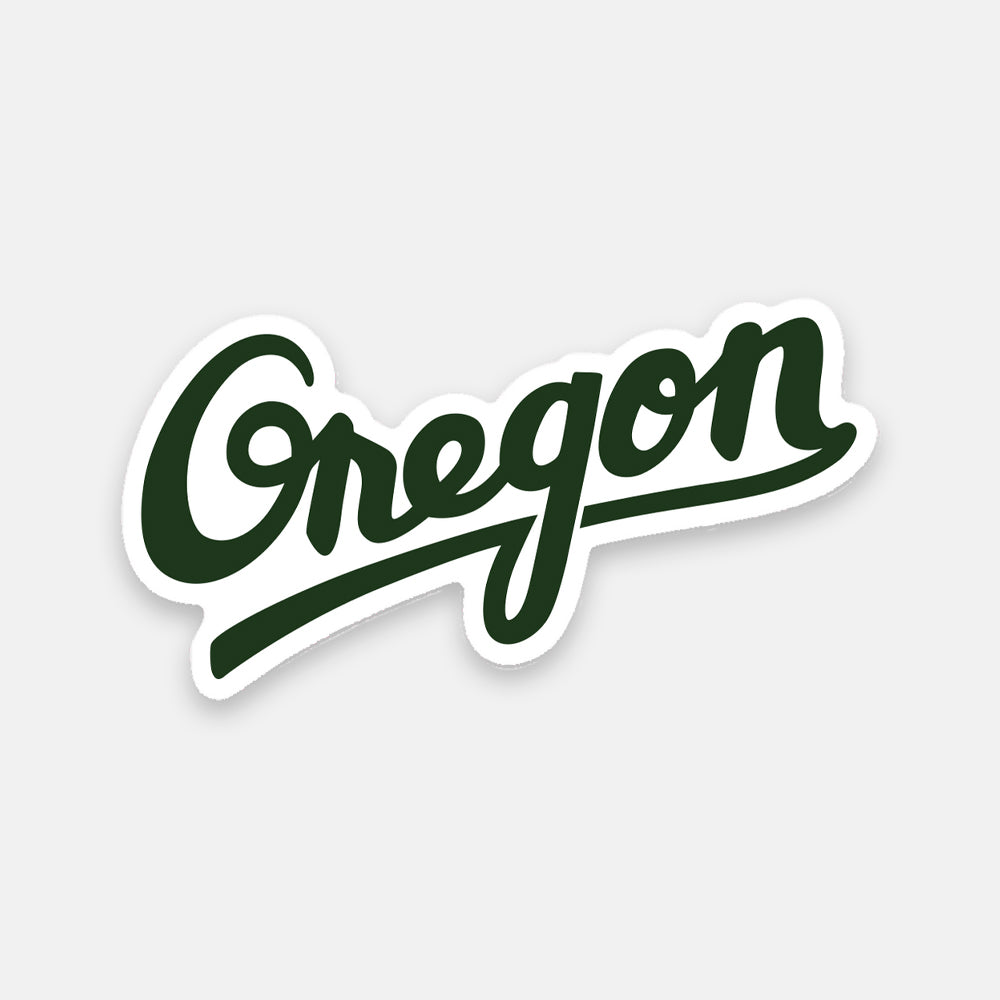 Dark green cursive text reading "Oregon," featuring a slight shadow outline, is elegantly displayed on a light gray background—ideal as an Oregon decal, and part of the 33rd Sticker collection.
