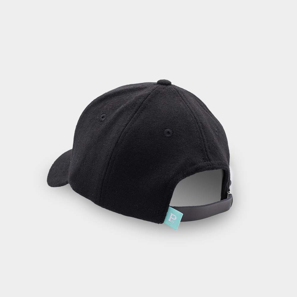 The Portland "P" Cap - Black, a classic SHELL PRODUCT, is displayed from the rear view. It features an adjustable strap with a metal buckle and includes a blue tag with a white "P" logo on the left side. The background is plain white.