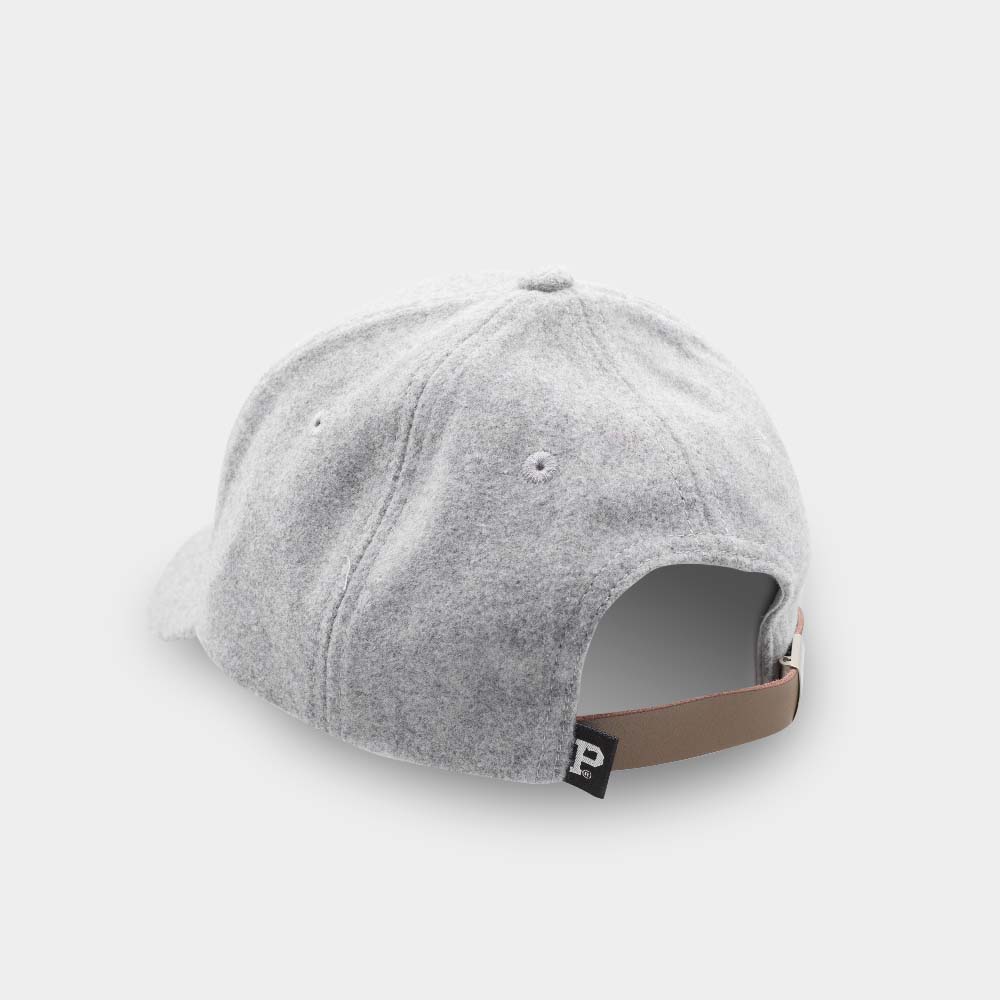 A rear view of the Portland "P" Cap - Light Grey, a new SHELL PRODUCT, with a beige adjustable strap featuring a black tab with a white letter "P" on it. The cap is lying on a plain white surface.