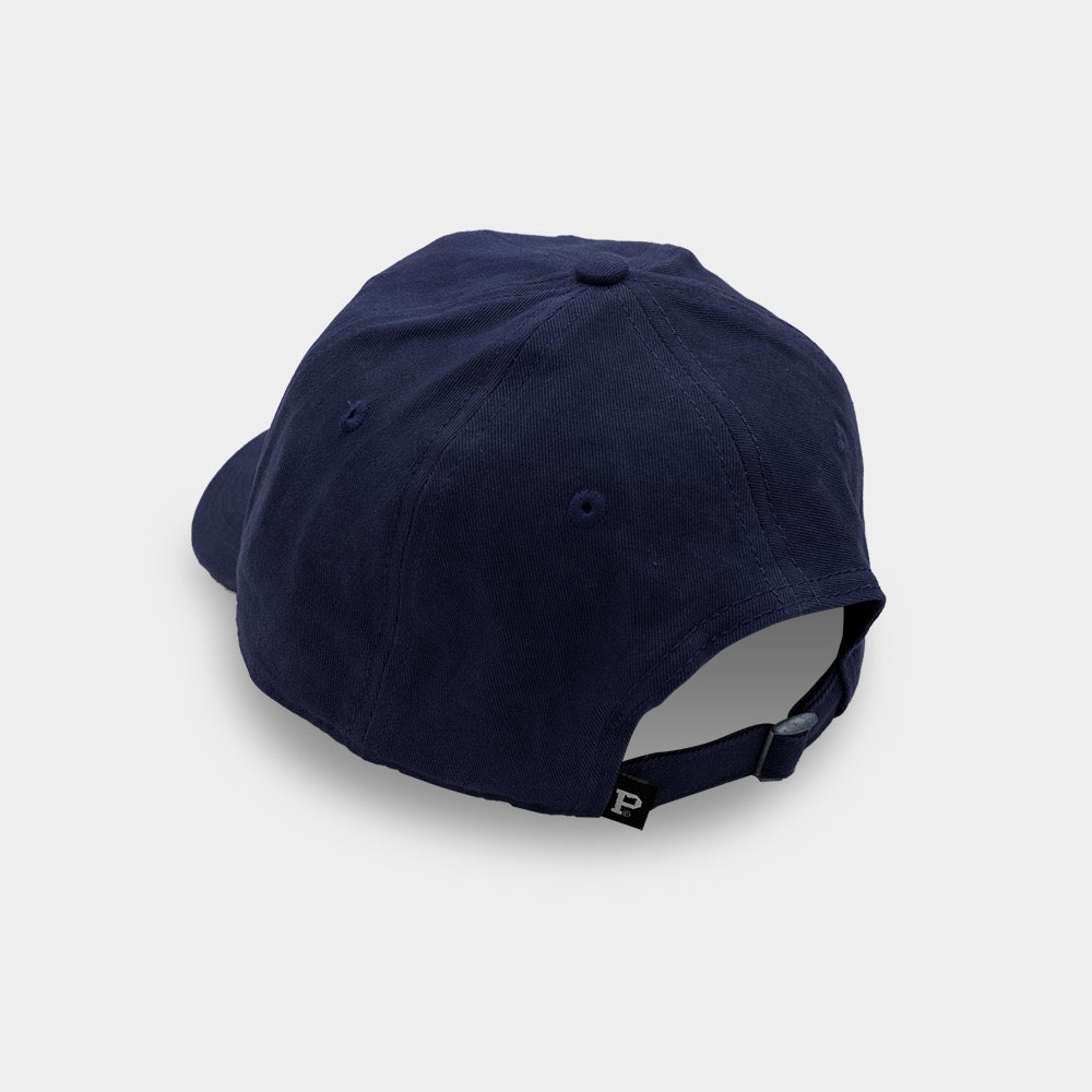 The Dad Hat - Navy is displayed from the back, showcasing its adjustable strap with a small black tag protruding from it. This SHELL PRODUCT boasts a minimalist design with no visible logos. The plain white background accentuates the hat's sleek simplicity.