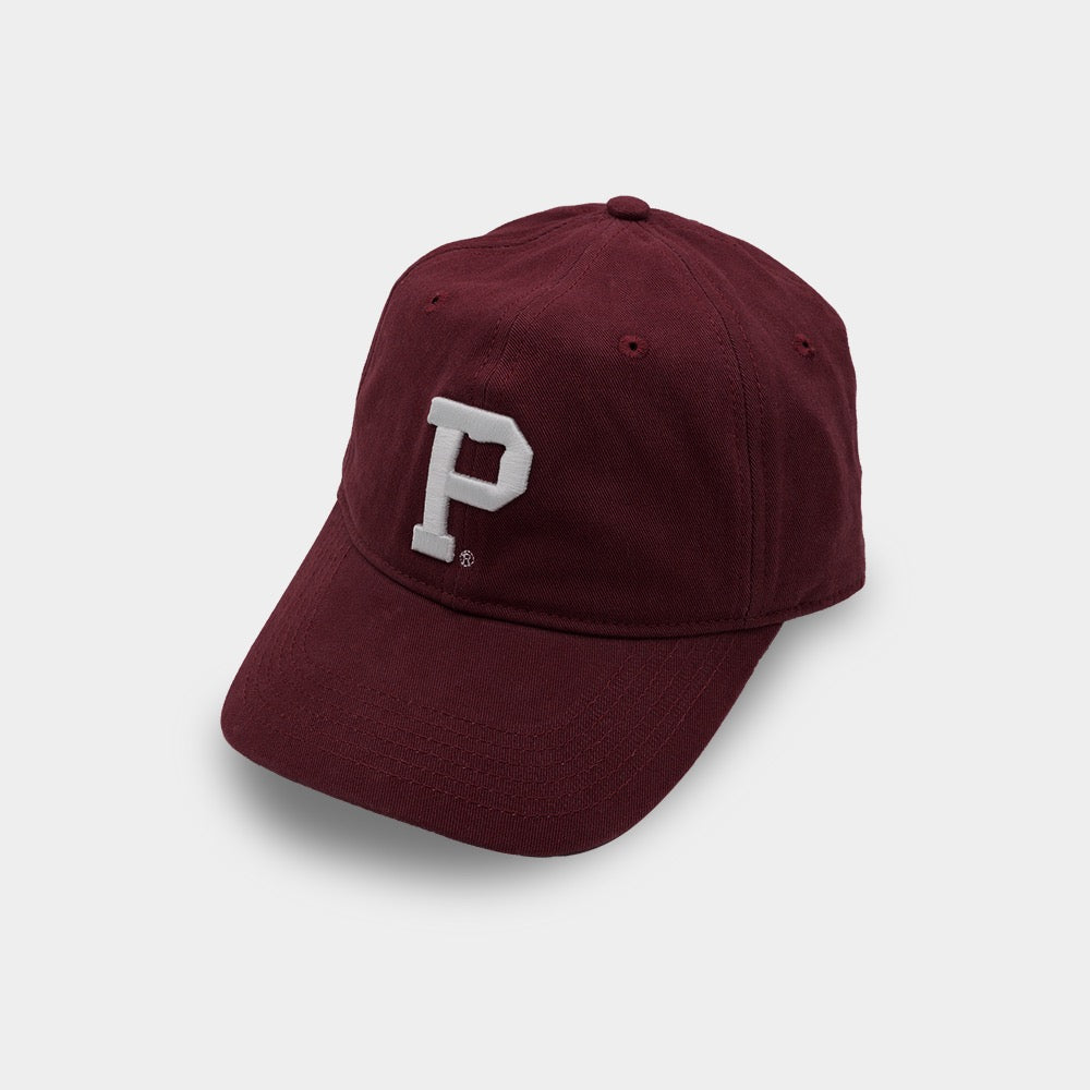 The Dad Hat - Maroon features a curved brim and an embroidered white letter "P" on the front. Positioned at a slight angle, this stylish accessory stands out against a plain, light grey background.