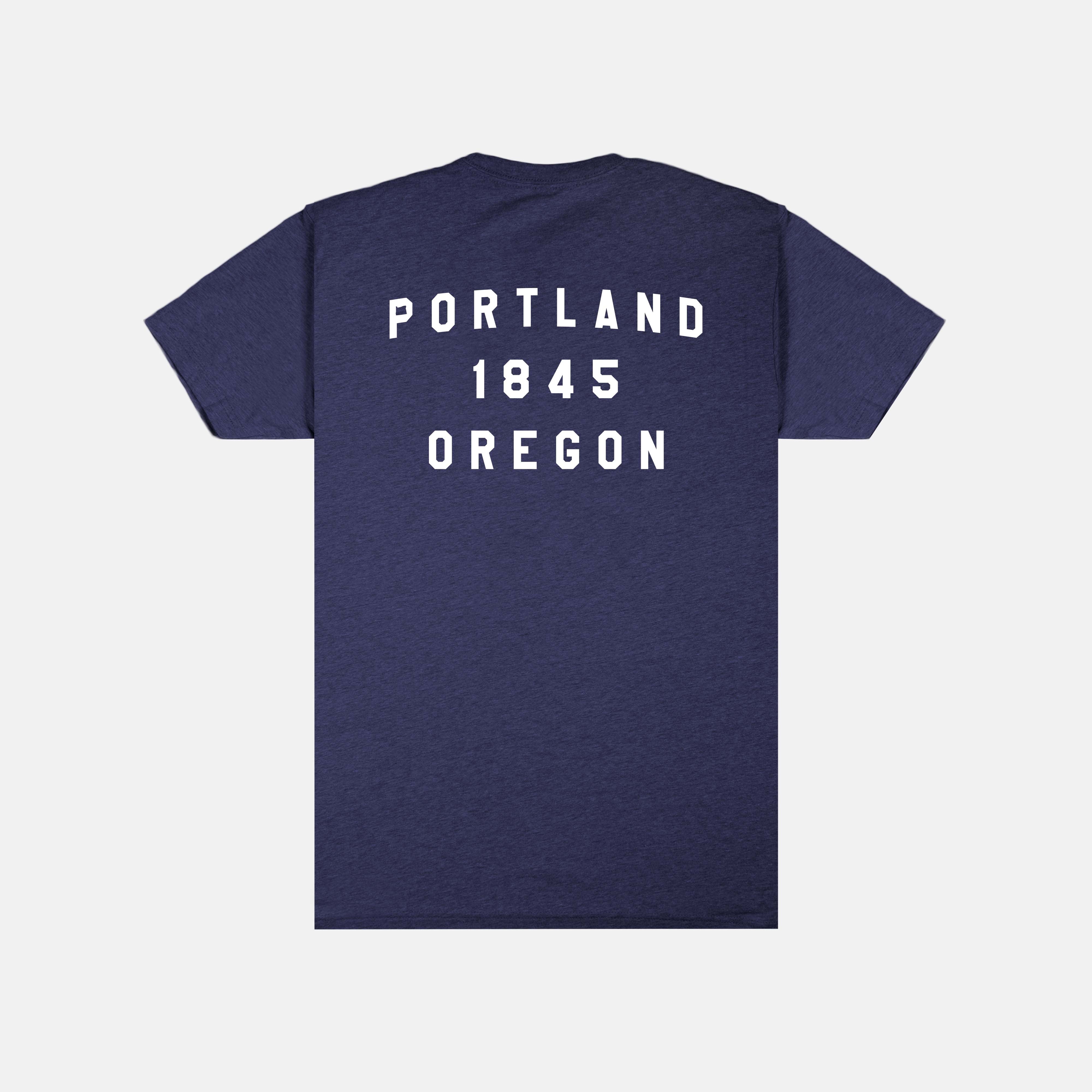 The Soft-Blend "P" Tee - Classic in heather navy showcases "PORTLAND 1845 OREGON" prominently in large, white capital letters on the back. This Portland Gear shirt offers a simple, timeless design free of additional patterns or graphics and is packaged sustainably.