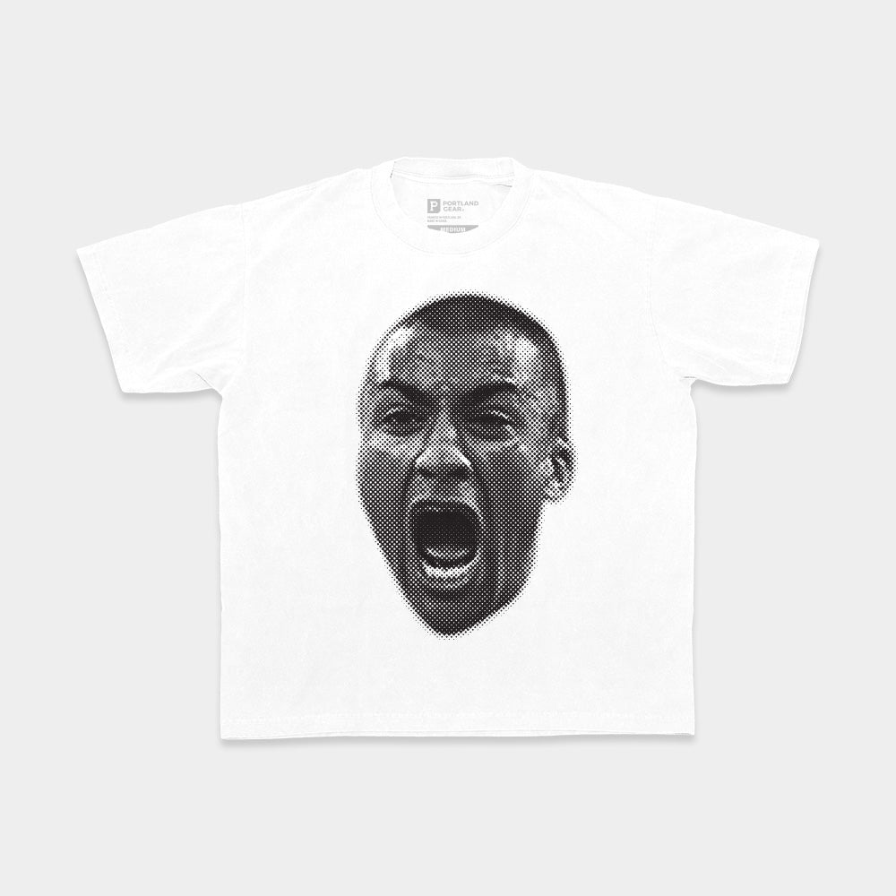 White t-shirt featuring a stylized black and white graphic of a person’s face in mid-shout or scream, inspired by the 2024 Olympics. The face has a dot matrix pattern, creating a bold contrast against the white fabric. The All-American Ashton Eaton Oversized Tee is laid flat against a white background.